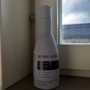 Björn Axén Volumizing Conditioner - Volymgivande balsam från Björn Axén med risprotein och skyddande polymerer. Flaskan är vit med lila etikett och har en smal, rundad form. Vegansk och dermatologiskt testad, innehåller 250 ml. Perfekt för dig som vill ha fylligare hår. Oöppnad 