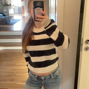 Randig stickad tröja i blått och vitt  - Säljer en ribbstickad tröja med breda blåa och vita ränder. Tröjan har rund halsringning och långa ärmar. Den är mjuk och skön, perfekt för lager-på-lager och chill dagar. Passformen är normal och materialet känns som bomull eller syntet. OBS, smuts vid ärmarna som inte går bort. 