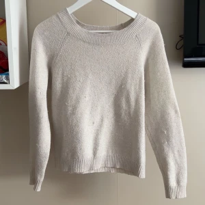 Beige stickad tröja från Vero Moda - Mysig beige stickad tröja från Vero Moda med rund halsringning och ribbade muddar vid ärmslut. Klassisk och stilren design som funkar året runt.