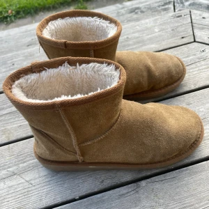 Uggs vinterskor - Mysiga bruna boots från McKinley i mockaimitation med mjukt vitt foder. Klassisk rund tå och platt sula, perfekta för kyliga dagar. Snygg och enkel design som passar till det mesta. Säljes i storlek 37.