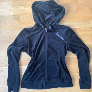 Svart velourhoodie från Gina Tricot - Mjuk och skön svart hoodie i velour från Gina Tricot. Tröjan har dragkedja framtill, huva med snörning och två fickor. Perfekt för chill dagar eller när du vill vara extra comfy.🌸✨