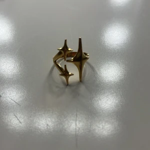 Guldig ring med stjärnformad design - En guldigring med tre stjärnor. Den är justerbar.