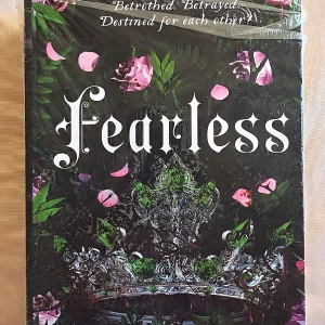 Fearless - En bok med en mystisk och lockande framsida prydd av en krona och rosor. Perfekt för dig som gillar spänning, romantik och episka berättelser om mod och öde. Sloganen antyder om svek, kärlek och ödesbestämda möten. Helt ny och inplastad.