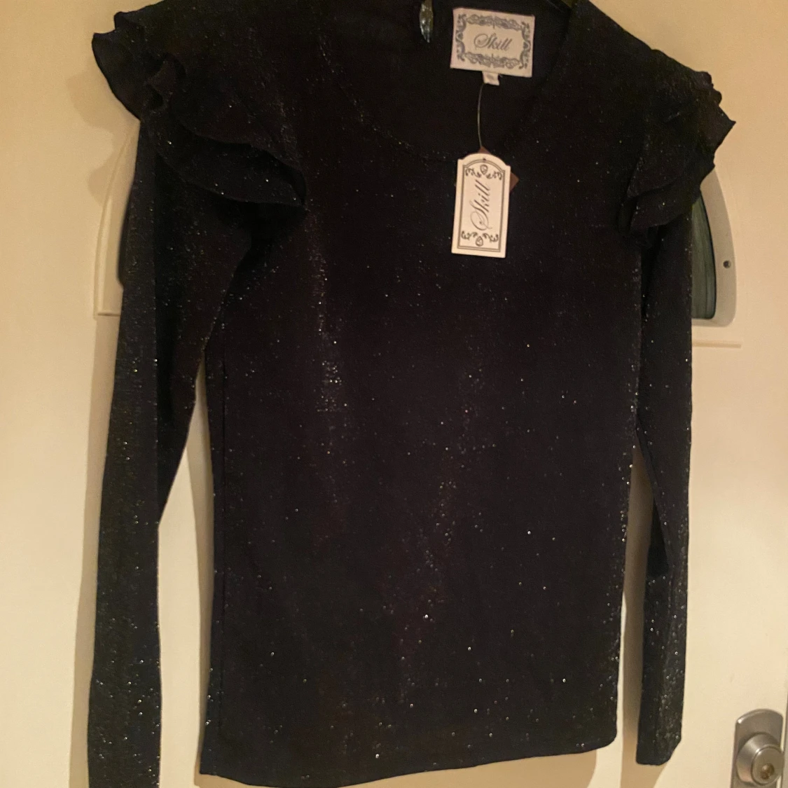 Svart glittrig topp med volang från Skill - 3