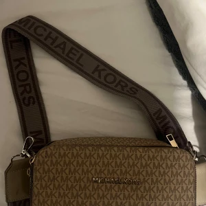 Beige axelremsväska från Michael kors  - Snygg beige axelväska från Michael Kors. Säljer då den inte längre är i min smak. Väskan är använd ett fåtal gånger och är i mycket bra skick