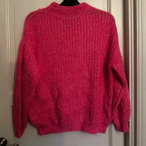 Rosa stickad tröja - Supermysig stickad tröja i en härlig rosa färg från FB Sister. Tröjan har en loose passform, ribbade muddar och hög hals. Passar storlek upp till L