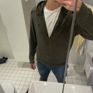 jacka/cardigan från Polo Ralph Lauren - Olivgrön hoodiejacka från Polo Ralph Lauren med dragkedja, huva och broderad logga på bröstet. Jackan är i mjuk bomullsmix med detaljer i polyester på axlar och huva. Perfekt för lager-på-lager och chill stil. Krävs bara en tvätt då den är lite skrynklig! Storlek m men passar lite mer som S! Axelbredd 44 och längd 57 cm! Jackan har två perfekta fickor, tyvärr kan jag lägg in fler bilder på plick! Skriv ifall du har frågor eller funderingar. Storlek M men passar S, (175-185) cm.