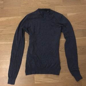 Mörkblå stickad tröja från lager 157 - En enkel och stilren mörkblå stickad tröja från lager 157. Tröjan har rund halsringning, långa ärmar och ribbade muddar vid ärmslut och nederkant. Perfekt för lager-på-lager och passar till det mesta.