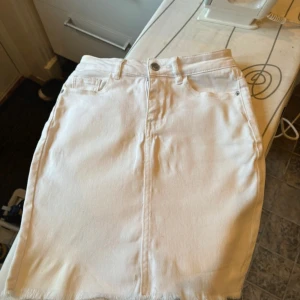 Vit jeanskjol från Amisu, storlek 34 - Säljer en vit jeanskjol från Amisu i storlek 34 stretchig. Kjolen har klassisk femficksdesign, knapp och dragkedja fram samt rå kant nedtill. Materialet är bomull med lite stretch och kjolen är kort i modellen. Perfekt för dig som gillar clean och enkel stil.