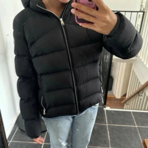Svart pufferjacka från Colmar - Säljer en svart pufferjacka från Colmar med huva och dragkedja framtill.  Den är i jätte fint skick. Äkta!! Köpt på Miinto 💖 De finns ett super duper litet hål på armen som inte syns alls. Du kan se på Sista bilden ( om de ens syns ) ❤️kan gå ner i pris om de är snabb affär. (s 46)