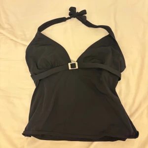 Svart fest-halterneck topp - Stilren svart fest-topp från Jasper Conran med halterneck och snyggt spänne framtill. Toppen har v-ringad urringning och knyt i nacken. 💕 Skulle säga Strl M men passar även S