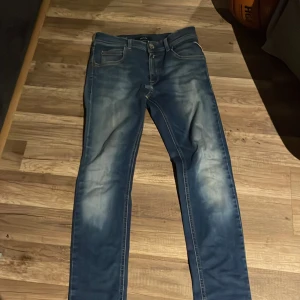 Replay Hyperflex blå jeans 14A - Säljer ett par blå Replay Hyperflex jeans i storlek 14A. Jeansen har en snygg tvätt med ljusa partier och klassisk femficksdesign. Stretchigt material för extra komfort och smal passform. Perfekta för dig som gillar stilrena och bekväma jeans.