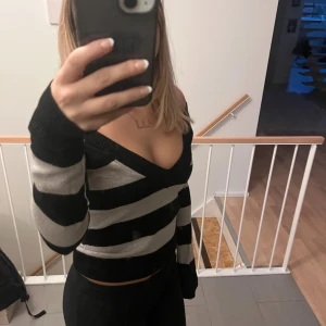 Randig croppad kofta of sholder vintage - Säljer en kofta med breda svarta och guld/silver ränder. Tröjan har djup v-ringning och långa ärmar. lite vintage, köpt på hm finns ej kvar💗