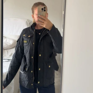 Svart quiltad jacka från Barbour  - Quiltad svart jacka från Barbour International med guldiga knappar, bälte i midjan, flera fickor och snygga detaljer. Storlek XL men sitter som S. Perfekt för hösten! 🍁inga defekter överhuvudtaget! Köpt för 4700