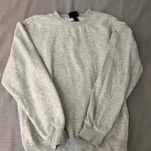 Grå sweatshirt i bomull - Enkel och stilren grå sweatshirt med rund hals och långa ärmar. Tröjan har ribbade muddar vid ärmslut och nederkant, perfekt för en avslappnad och clean look. Tillverkad i mjuk bomull för maximal komfort.