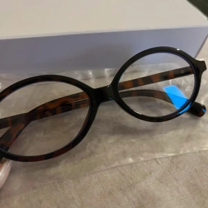 Blåljus glasögon  - Snygga runda glasögon med leopardmönstrad båge i bruna och svarta toner. Bågarna har coola guldfärgade nitar på sidorna som ger en extra edge. Perfekt accessoar för dig som vill sticka ut med en trendig och retroinspirerad look.