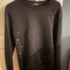 Sweatshirt Dsquared2 - Cool svart sweatshirt från Dsquared2 med diskret logga på bröstet och färgstänk i rött och vitt. Tröjan har rund halsringning och långa ärmar. 