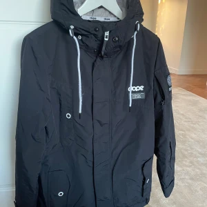 Skidjacka från Dope, 2XS - Svart skidjacka från Dope med huva( plats för hjälm under) och vita detaljer. Vind/vattentålig. Passar ålder 13-15 år.