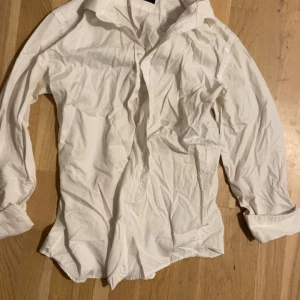 Vit skjorta från Sand, storlek 40 - Klassisk vit skjorta från Sand i storlek 40. Skjortan har lång ärm, knappar framtill och en snygg krage. Tillverkad i bomull för en skön känsla och stilren look. Perfekt för dig som gillar enkel och tidlös design.