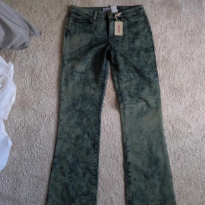 Acid wash bootcut jeans John Baner - Snygga acid wash jeans från John Baner i bootcut-modell. Byxorna är blågrönaktiga med coolt mönster och klassiska fem fickor. Materialmix med bomull och polyester, perfekt för dig som gillar retrovibbar och unik stil.