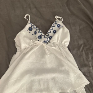 Vit broderad linnetopp med knyt - Supersöt vit linnetopp som har ett väldigt tunt och luftigt tyg som passar perfekt till varma dagar till bas linne under koftor för nu till hösten 😍 använd ca 5, tveka inte att fråga vid mer funderingar 🥰