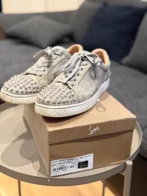 Gråa Christian Louboutin  - Säljer ett par gråa sneakers från Christian Louboutin .Skorna har snörning, rund tå och platt sula. Materialet är mocka och insidan är mjukt fodrad. Perfekt för dig som vill sticka ut med en lyxig och edgy stil.  *Inte Äkta*   Pris ej hugget i sten🪨