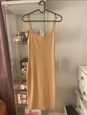 Beige långklänning från Zara  - Säljer en stilren beige långklänning från Zara Trafaluc i storlek S. Klänningen har smala axelband och en rak, figurnära passform. Materialet är mjukt och stretchigt, perfekt för dig som gillar minimalistisk och clean stil.