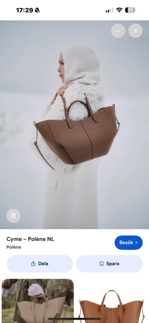 Brun handväska Polène Cyme L  - Snygg och stilren brun handväska från Polène, modell Cyme Mini. Väskan har en unik, skulptural form med två handtag och en avtagbar axelrem. Tillverkad i slätt skinn med diskreta sömmar och minimalistisk design. Perfekt för dig som gillar trendiga accessoarer.