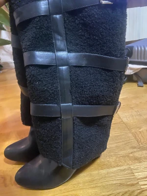 Unika svarta boots med päls och spännen - Säljer ett par riktigt coola svarta boots med spetsig tå och hög skaft i teddy-liknande material. Skorna har flera breda läderremmar med silverspännen som detaljer. Perfekta för dig som vill sticka ut med en edgy och trendig look.