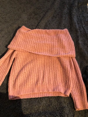 Rosa offshoulder stickad tröja Gina Tricot - Supermysig stickad tröja från Gina Tricot i en ljusrosa ton. Tröjan har offshoulder-design med bred krage och grovstickad struktur. Perfekt för att hålla sig varm och ändå se chill ut. Långärmad och loose passform.