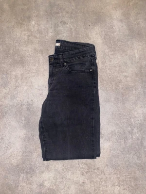 Levi's 711 Skinny svarta jeans - Svarta skinny jeans från Levi's. Snyggt smal passform. Jeansen är tillverkade i stretchigt denim som sitter tajt och bekvämt längs benen. Perfekt för dig som gillar en stilren och modern look.