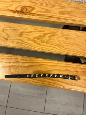 Svart valentino armband  - Säljer ett svart armband guldiga pyramidformade nitar längs hela bandet. Bältet har en klassisk metallspänne och är gjort i skinnimitation med en rå och edgy vibe. Perfekt för att ge din outfit lite extra attityd. Det kostar runt 2000 nytt mitt pris 599