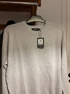 Ljusgrå stickad tröja från Dressmann - En snygg stickad tröja från dressmann. Beställde den på nätet och den var för stor för mig därför jag säljer. 300kr ny pris 