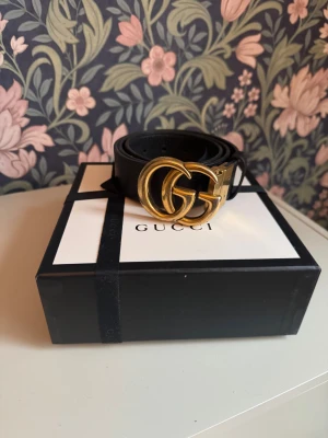 Svart Gucci skärp med GG-spänne - Säljer ett svart skärp från Gucci med ikoniskt dubbelt GG-spänne i guld. Bältet är gjort i äkta skinn och har en klassisk, stilren design som lyfter vilken outfit som helst. Reversible- svart på ena sidan och mörkbrunt på andra. 