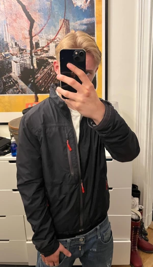 Blå Helly Hansen jacka - Säljer en mörkblå vindjacka från Helly Hansen. Den har en klasisk design och många fickor. 