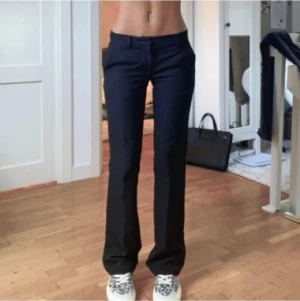 Svarta bootcut kostymbyxor - Snygga svarta kostymbyxor med bootcut-snitt och låg midja. Byxorna har klassiska fickor fram och bak, samt hällor för bälte. Passar perfekt till sneakers och ger en clean och stilren look.