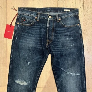 Mörkblå jeans från tramrossa - Snygga mörkblå jeans från Tramrossa med slitna detaljer och använda sparsamt. Jeansen har raka ben. Storlek 33. Priset kan diskuteras vid en snabb affär 