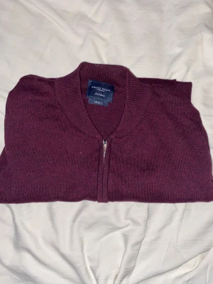 Vinröd kofta från Grand Frank - Vinröd stickad kofta från Grand Frank med ribbad krage och muddar. Koftan har hel dragkedja framtill och är långärmad. Perfekt för dig som gillar stilrena och klassiska plagg med en modern touch. Materialet är mjukt och skönt stickat.