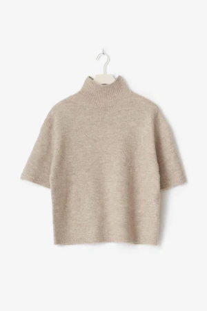 Beige stickad polotröja från Gina tricot - Säljer en beige stickad polotröja från Gina tricot med korta ärmar och hög krage. Tröjan har en loose passform och är tillverkad i mjukt material som känns skönt mot huden. Perfekt att styla med jeans eller kjol för en chill look.
