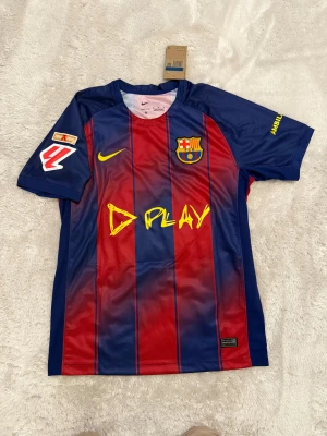 FC Barcelona Pedri #8 matchtröja Nike - Säljer en officiell FC Barcelona matchtröja med Pedri #8 på ryggen. Tröjan är kortärmad och har klassiska blå och röda vertikala ränder, klubbmärke på bröstet och gula detaljer. Tillverkad i lätt polyester med tryckta sponsorloggor och UNHCR-emblem.