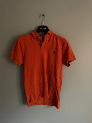 Orange piké från Polo Ralph Lauren S - Säljer en orange pikétröja från Polo Ralph Lauren i storlek S, slim fit. Klassisk krage, korta ärmar och broderad logga på bröstet. Tillverkad i mjuk bomull som känns skön mot huden. Perfekt för dig som gillar stilren och sportig look.