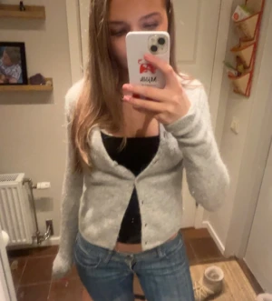 Ljusgrå croppad kofta med knappar - Säljer en ljusgrå, croppad kofta med knappar framtill. Materialet är en blandning av alpaca! Koftan har lång ärm och är stickad i ett mjukt material som känns skönt mot huden. Perfekt att slänga över en topp för en chill look. Passar dig som gillar enkel och stilren vibe. Säljer en likadan i marinblå också! 🩷