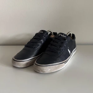 Svarta sneakers från Polo Ralph Lauren - Svarta sneakers från Polo Ralph Lauren med klassisk låg profil, snörning och vit logga på sidan | Storlek: 40 | Perfekta för en clean och stilren look.