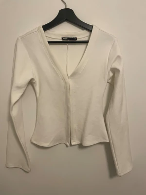 Vit v-ringad topp från Bik Bok - Säljer min vita tröja från Bik Bok i storlek XS pga att den inte kommer till användning. Om de inte framgår på bilden är den en väldigt kritvit färg och jag har använt den en gång då jag behövde en sådan tröja till ett foto men efter inte använt. Skriv vid funderingar!🩷