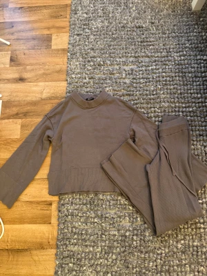  Stickad tröja och byxor från Gina Tricot - Säljer en stickad tröja och byxor från Gina Tricot i storlek XS. Tröjan har en ribbad hög hals och breda muddar vid ärmslut och nederkant. Modellen är loose fit med långa ärmar och mjukt material som känns skönt mot huden. Perfekt för chill dagar.