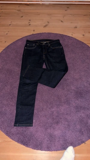 Levi's 512 mörkblå jeans W31 L32 - Snygga Levi's 512 jeans i mörkblå tvätt med klassiska kontrastsömmar och fem fickor. Modellen har en slim passform med något smalare ben och normal midja. Perfekt för dig som gillar stilrena och tidlösa jeans.