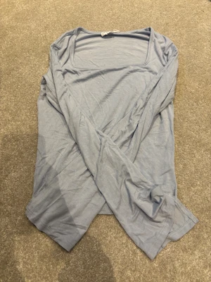 Ljusblå långärmad topp XOXO friends - Ljusblå långärmad topp från XOXO friends med fyrkantig ringning. Tunn och mjuk i materialet, perfekt för lager-på-lager eller som den är. Enkel och stilren design som passar till det mesta.