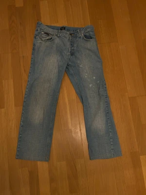 Blå jeans från Dolce & Gabbana - Snygga ljusblå jeans från D&G med klassisk femficksdesign och stort D&G-tryck på bakfickan. Jeansen har raka ben och normal passform, tillverkade i mjukt denim med slitningar och unika detaljer framtill. Perfekt för dig som gillar street och designer. För störa för mig men jag har 32 31 igentligen och med bälte så ser dom bra ut. Pris kan distuteras 