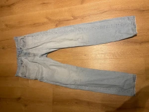 Levis 501 ljusblå jeans straight fit - Ljusblå Levis 501 jeans med klassisk straight fit och fem fickor. Jeansen har hög midja, knappgylf och ikonisk Levis-lapp baktill. Tillverkade i slitstarkt bomullsjeansmaterial, perfekta för en chill och tidlös look. 28/32, och med en snygg tvätt