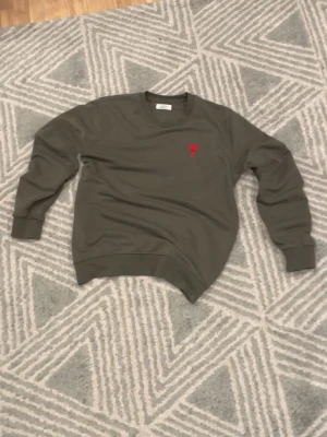 Olivgrön sweatshirt från Ami Paris - En väldigt stilig och skön tröja ifrån Ami Paris, riktigt clean olive grön färg, passar perfekt nu inför höstens alla mörka dagar. Passar fint med det mesta. Aldrig använt, sprillans ny! 🙌🤩